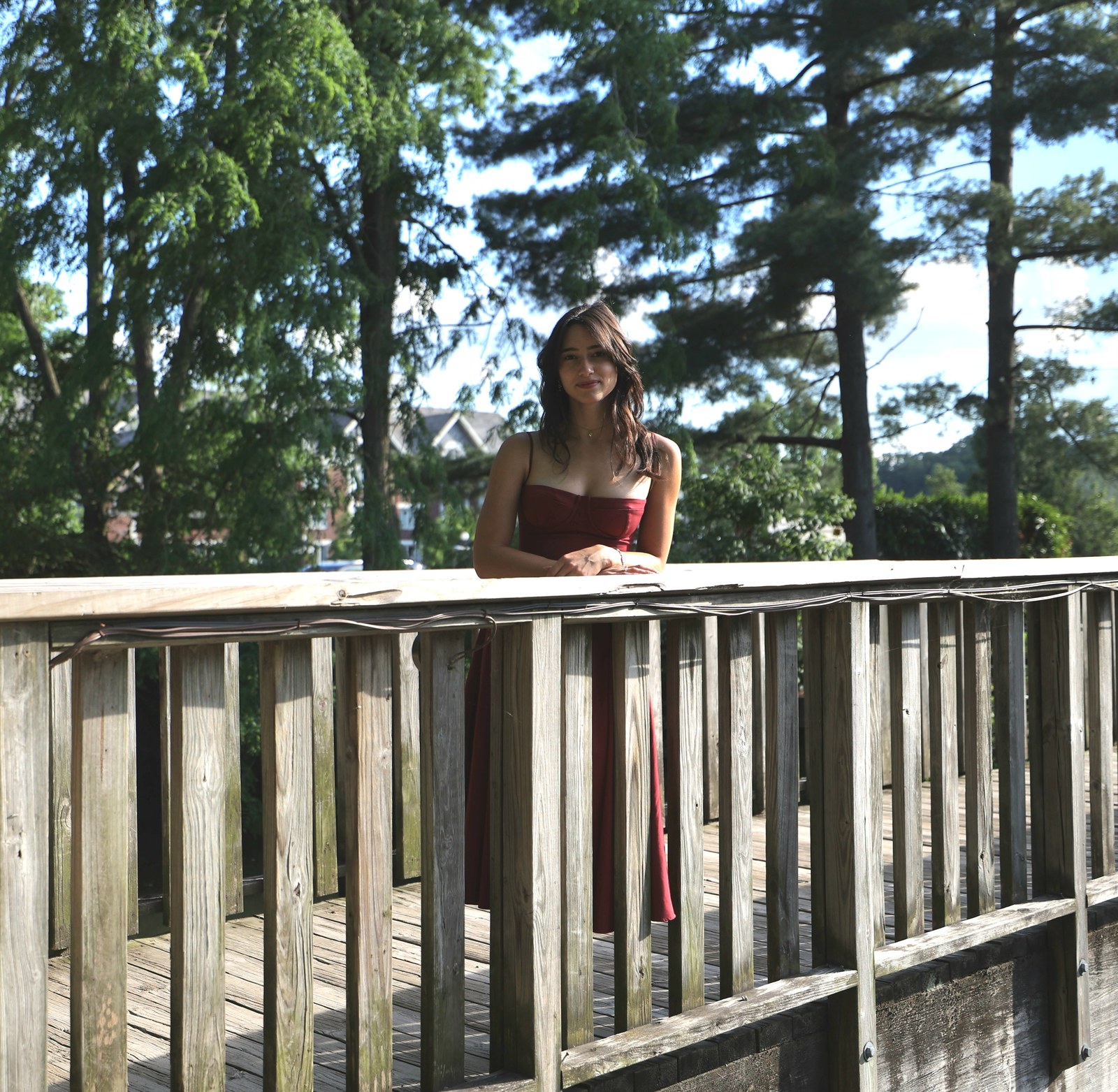 Aubrey, maker at Fellchaser Studio, standing on a wooden bridge in the sunlight